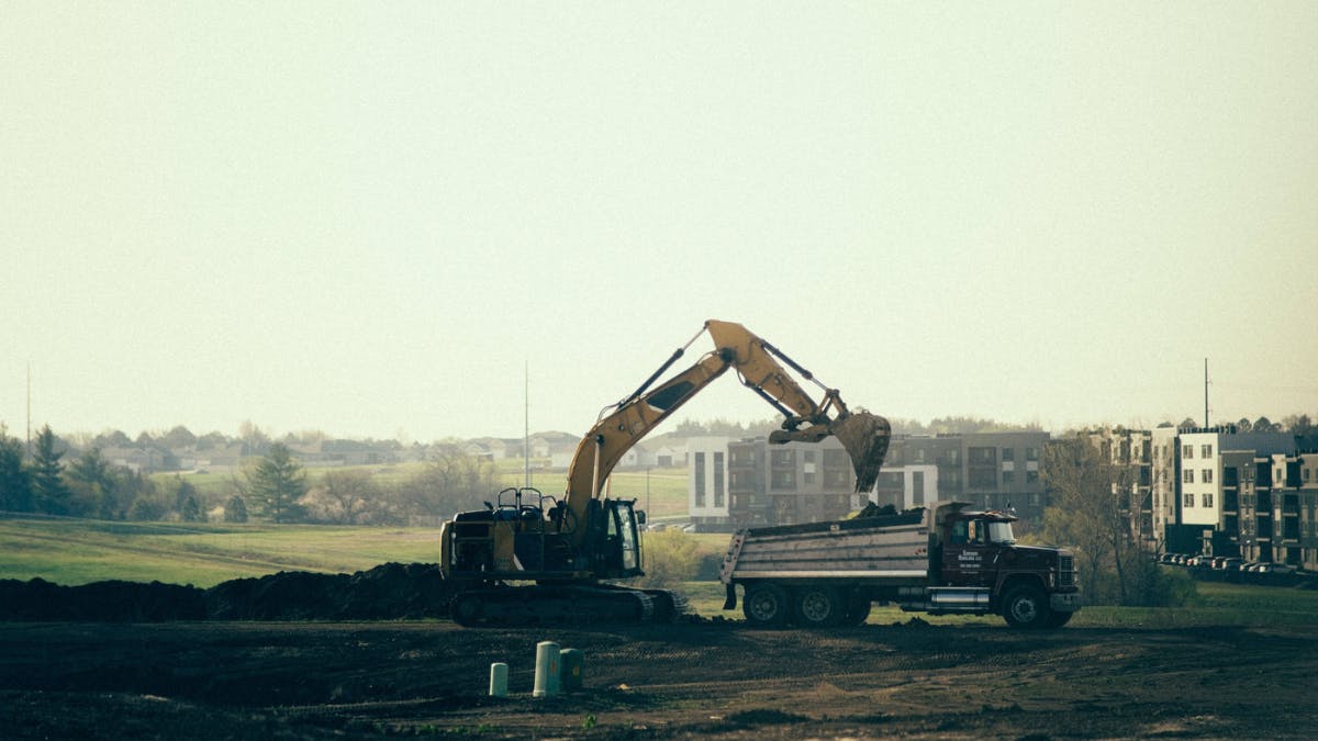 Excavator loading soil into a dump truck at a residential development project.