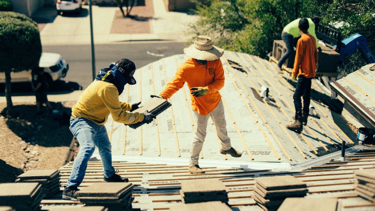 Roofers install metal roofing panels on residential job site.