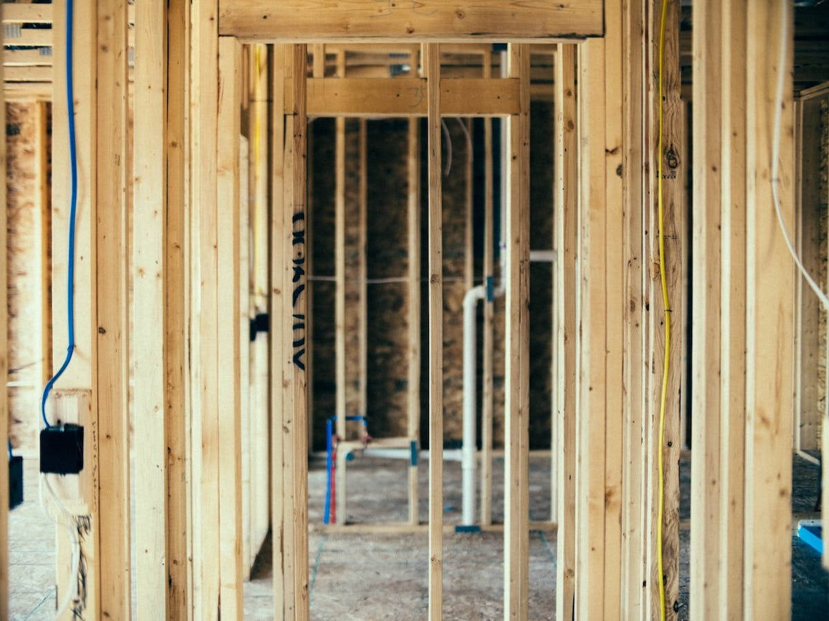 nterior framing shows exposed wall studs with plumbing and electrical rough-in underway.