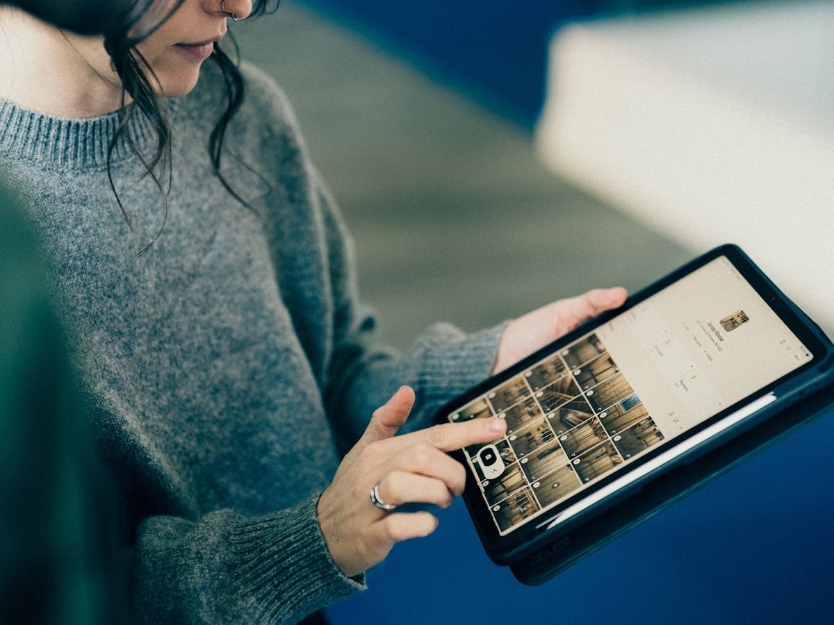 Woman using a tablet on a jobsite to view a construction project dashboard with photo updates and site progress details.